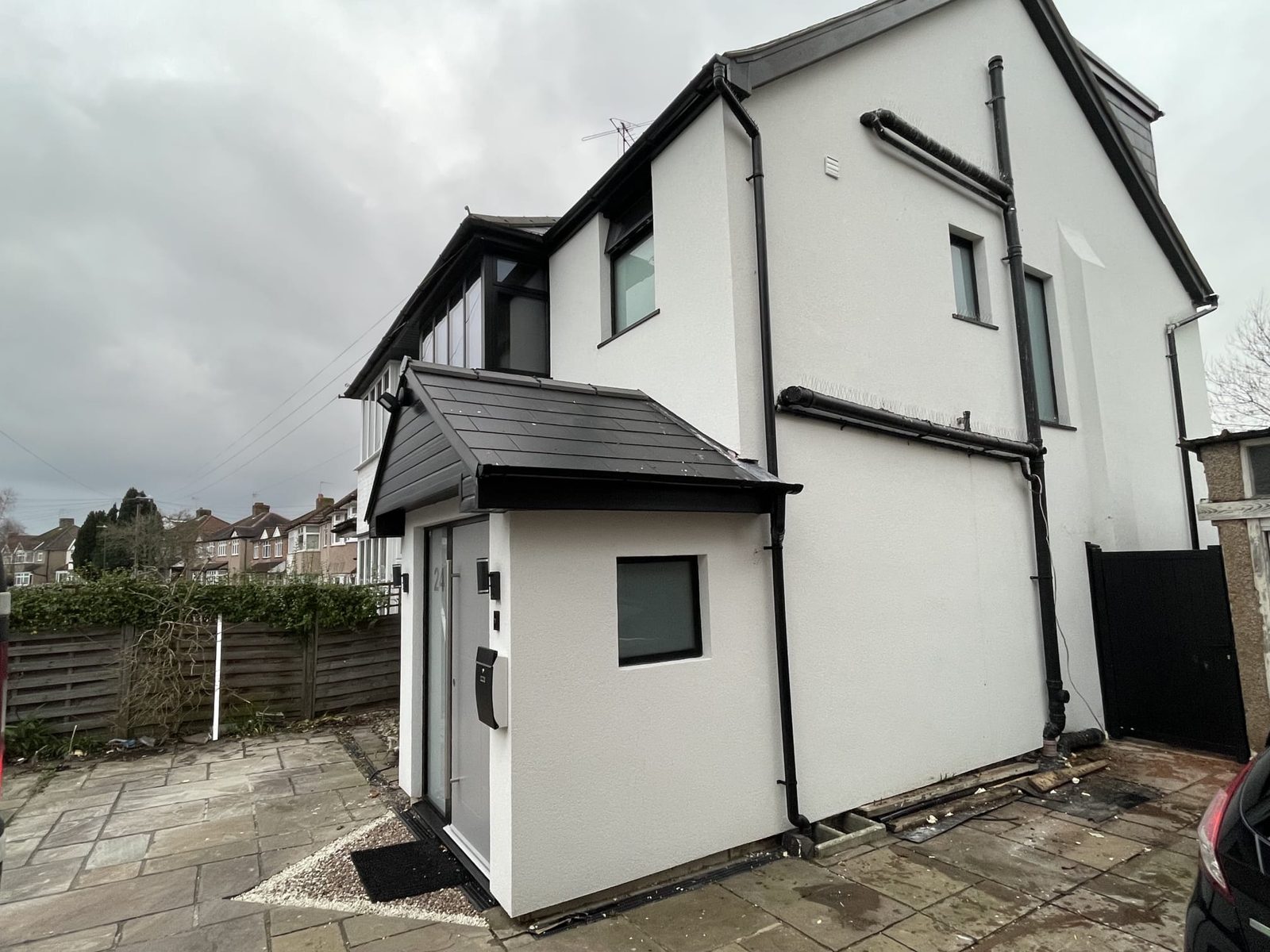 Side elevation of a freshly rendered semi-detached home with black rainwater goods